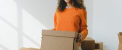 Young woman carrying cardboard box during relocation - student moving guide
